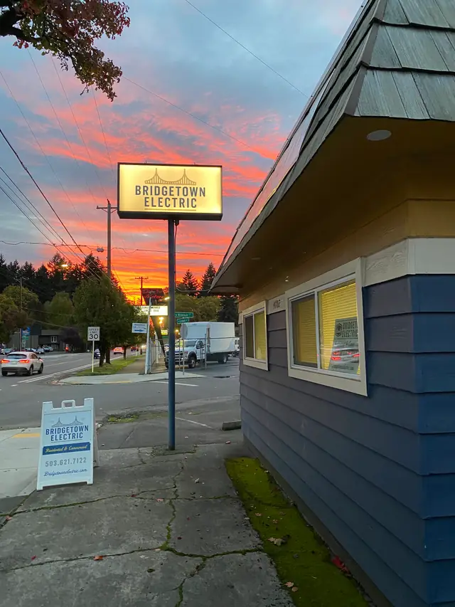 The illuminated Bridgetown Electric pole sign and shopfront on N Lombard Street at sunset